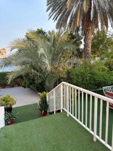 a white wooden staircase leading to a yard with palm trees at Al Ramla, Na’eem Bin Masoud St#8, Villa#10 in Sharjah