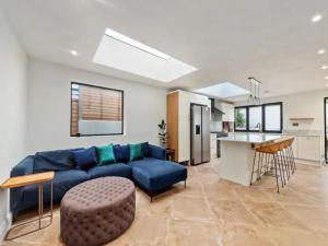 a living room with a blue couch and a kitchen at Pass the Keys Modern and luxury London house in London