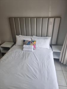 Una cama con sábanas blancas y almohadas. en The Blyde Riverwalk Estate, en Pretoria