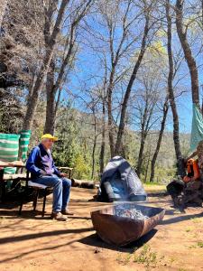 a man sitting on a bench next to a tent at Camping don Zacarías in El Bolsico