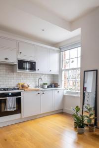une cuisine blanche avec des placards blancs et une fenêtre dans l'établissement Veeve - Good Vibrations, à Londres