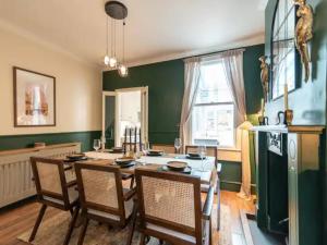 a dining room with a table and chairs and a green wall at Pass the Keys Welcoming terrace with free street parking in Bath