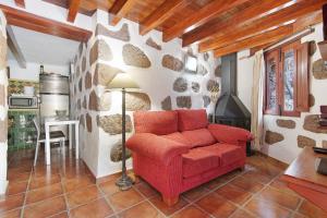 ein rotes Sofa im Wohnzimmer mit einer Steinmauer in der Unterkunft Bentayga Sensation in El Chorrillo