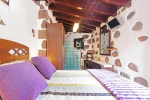 ein Schlafzimmer mit einem Bett in einem Zimmer mit einer Steinmauer in der Unterkunft Bentayga Sensation in El Chorrillo