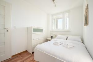 a white bedroom with a bed and a window at Metro Targówek Comfy Apartment in Warsaw