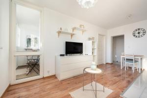 a white living room with a television and a table at Metro Targówek Comfy Apartment in Warsaw