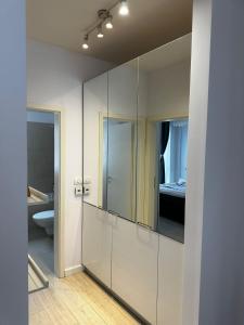 ein Badezimmer mit weißen Schränken und einem Spiegel in der Unterkunft Anastasia Apartment in Timişoara