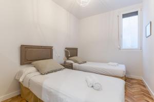 2 camas en una habitación con paredes blancas y ventana en Spacious Central-3Bedrooms 3Bathrooms-Sol, en Madrid
