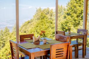 a table and chairs on a porch with a view at SHIVAYA since 1953 , Mukteshwar in Mukteshwar