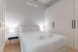 a white bedroom with a white bed and a table at Cozy and Central-1Bd 1Bth- Cortes in Madrid