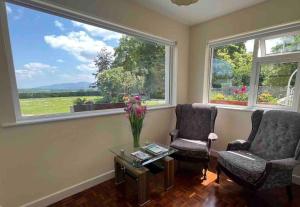 sala de estar con 2 sillas, mesa y 2 ventanas en Beautiful Farmhouse an Hour’s Drive From Four Irish Cities en Clonmel