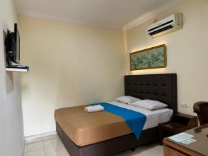 a bedroom with a bed with a blue blanket at Hotel Priangan in Cirebon