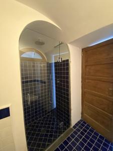 a bathroom with a shower with blue tiles and a door at Monacone vista mare in Capri