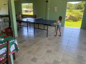 a little girl playing ping pong in a room at Pousada do colono in Morretes