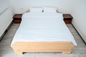 Una cama grande con sábanas blancas encima. en Pensiunea Abrudan, en Scrind-Frăsinet