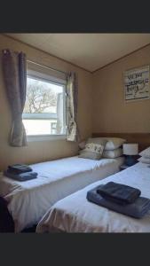 two beds in a room with a window at Pinto Holiday Home Oakdene Forest Park Passes Inc! in Ringwood