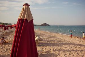 a beach with a red umbrella and people on it at Villa Louise in Costa Rei