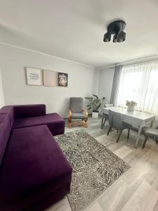een woonkamer met een paarse bank en een tafel bij Apartament Morskie Oko in Brodnica