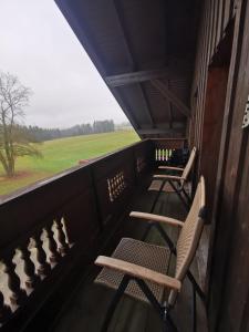 d'un balcon avec des chaises et une vue sur un champ. dans l'établissement Cafe zum Toni, à Thyrnau