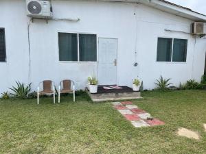 duas cadeiras sentadas em frente a uma casa branca em EL HOGAR em Accra