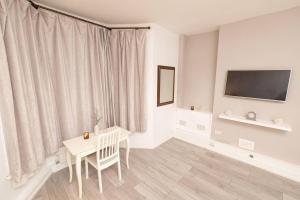 a white room with a table and a tv at Beautiful 2-Bed Haven In Chelsea in London