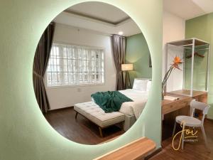 a bedroom with a bed and a desk and a mirror at Joi Hospitality - Central in Vung Tau