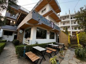 un restaurant avec des tables et des bancs devant un bâtiment dans l'établissement 12 Monks Rishikesh Hostel, à Rishikesh