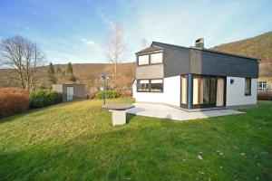 a black and white house with a bench in a yard at Symon Lodge in La Roche-en-Ardenne