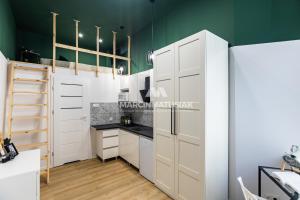 a kitchen with white cabinets and a green wall at Boat City Aparts - Dworzec Łódź Fabryczna in Łódź