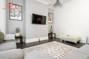 Spacious 5-Bedroom Oasis with Games Room-Liverpool في ليفربول: غرفة معيشة مع أريكة وتلفزيون على الحائط
