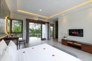 a bedroom with a bed and a desk and a tv at Taman Dharmawangsa Suites in Nusa Dua