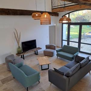ein Wohnzimmer mit Sofas und Stühlen sowie einem TV in der Unterkunft Grange 8 personnes in Billère