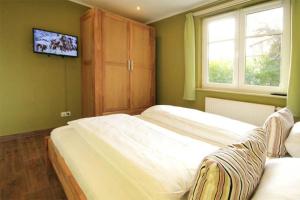 a bedroom with two beds and a tv on the wall at Strandschloesschen-Haus-II-WE-1-9809 in Kühlungsborn