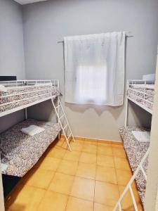 a room with three bunk beds and a window at Albergue la Fontanina in Mata de Alcántara