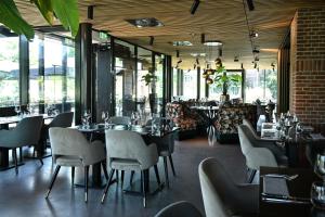 un ristorante con tavoli e sedie in una stanza con finestre di Wapen van Hengelo Residence Suites - digital key by email a Hengelo