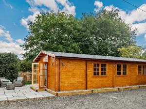 a wooden shed with a window and a patio at 2 Bed in Saxmundham 89929 in Snape