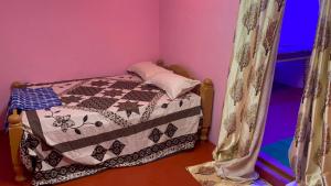 a small bedroom with a bed with a quilt on it at Coorg Green Moon in Madikeri