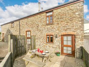 a stone cottage with a wooden table and a bench at 1 Bed in Newquay 89942 in Mawgan Porth