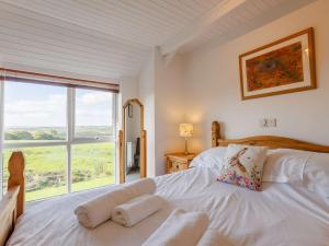 una camera con un letto bianco e una grande finestra di 5 Bed in Widemouth Bay 89900 a Week Saint Mary