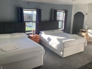 two beds in a bedroom with two windows at The Riverside in Sutton Bridge