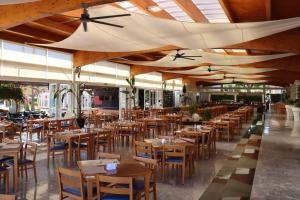 ein Restaurant mit Holztischen, Stühlen und Decken in der Unterkunft Aparthotel Ciudad Laurel in Cala Millor