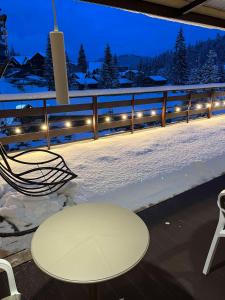 uma mesa e cadeiras num deque com neve em Zdybanka em Bukovel