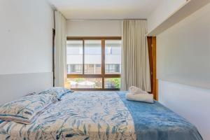 Camassari的住宿－IT08 Apto 3/4 a 50m da Praia - Itacimirim，一间卧室设有一张床和一个大窗户