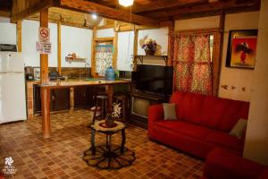 a living room with a red couch and a kitchen at La Cabaña de Blanca in Jalpan