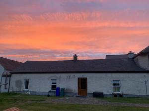 ein weißes Haus mit Sonnenuntergang im Hintergrund in der Unterkunft Wildflower Cottage in Clonmel