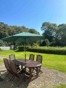 a wooden table with chairs and an umbrella at Wildflower Cottage in Clonmel