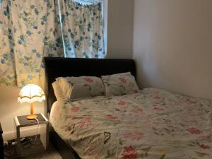 a bedroom with a bed with a lamp and a window at Feel at home in Abbey Wood