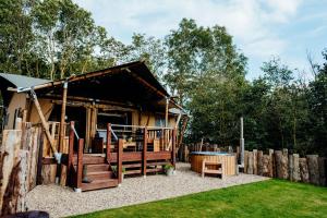 een houten huis met een speeltuin in de tuin bij Fibden Farm Glamping - Luxury Safari Lodge in Droitwich
