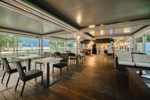 een restaurant met tafels, stoelen en ramen bij Seven Park Hotel Lake Como - Adults Only in Colico