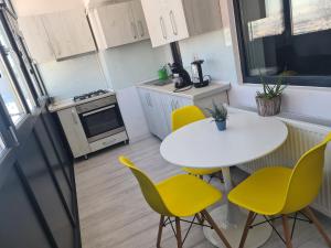 una piccola cucina con tavolo bianco e sedie gialle di Luxury Mall Q4 Apartment a Bacău